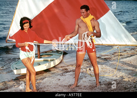 man and woman rigging small sailboat by lake Stock Photo
