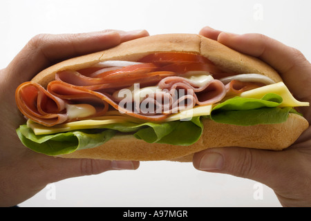 Hands holding ham and cheese sub sandwich FoodCollection Stock Photo