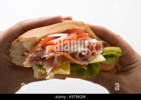 Hands holding ham and cheese sub sandwich FoodCollection Stock Photo