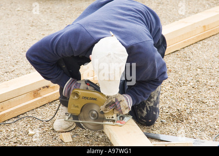a carpenter using an electric circular saw to cut a length of timber Stock Photo