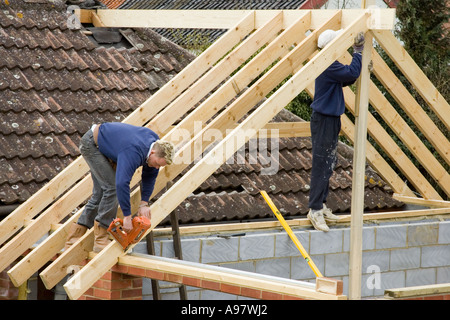 builders constructing a new roof for an extension to a home using a nail gun Stock Photo