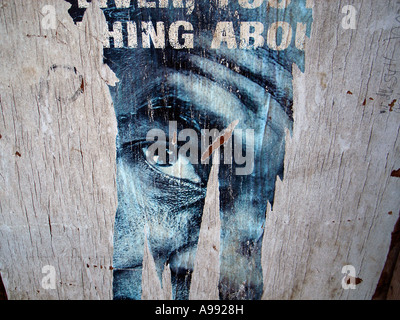 Torn advertisement with eye and face old paint on exterior wall forms an abstract urban texture pattern Stock Photo