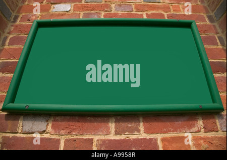 Old green sign on a red brick wall unusual perspective blank for your text Stock Photo