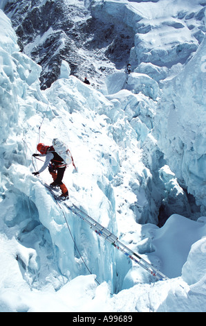 Mountain climber uses a ladder to cross a gorge in the Khumbu Icefall region on Mt Everest Two other climbers preceeded him Stock Photo