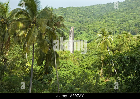 The lush verdant rain forest encroaching on the ruins of a tall chimney stack belonging to an old Sugar Plantation, St Kitts Stock Photo