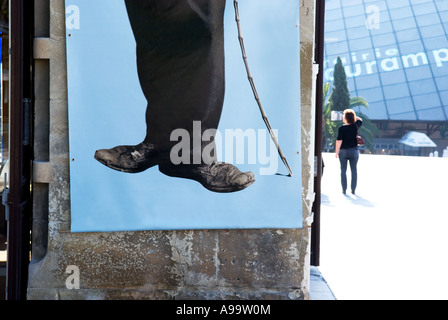 a cropped view of charlie chaplin's feet on a poster with a person in a public square in the background Stock Photo