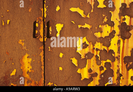 Detail of a yellow painted rusting metal cabinet or cupboard from which most of the paint has flaked away Stock Photo