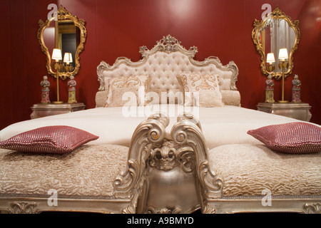 Silver finished capitonè bed with dormeuses at its feet in red wall bedroom Stock Photo