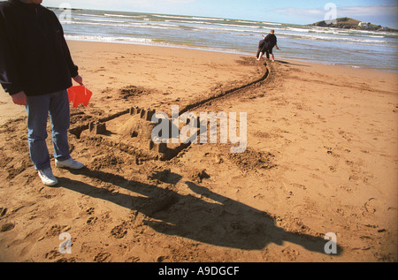 Building sandcastles on Thurlestone beach Devon UK, with Burgh Island in the background. Stock Photo