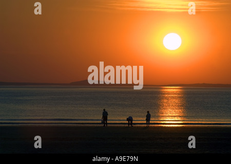 Family on beach at Broadhaven at sunset Pembrokeshire Dyfed West Wales ...