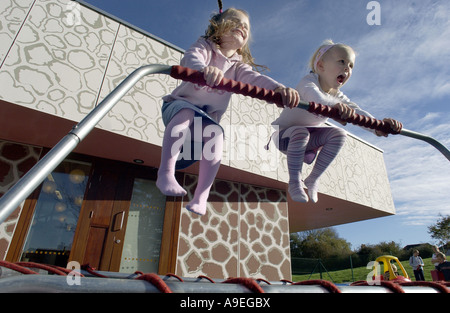 Two four 4 year old girls bounce with glee on a trampoline Stock Photo