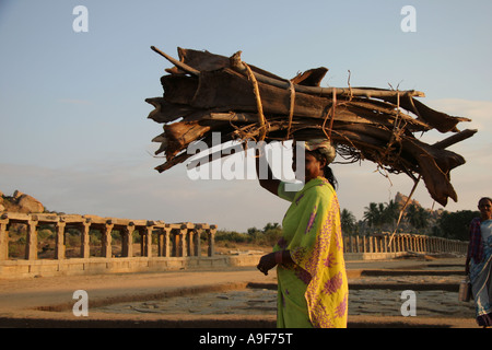 A local Indian woman carries her load of wood on her head on Courtesan's Street in Hampi, Northern Karnataka, India Stock Photo