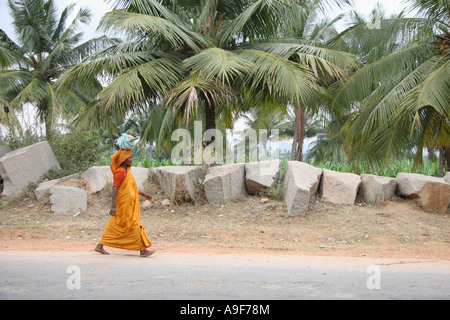 A Indian woman walks down the street carrying her belongings on her head in Hampi, Northern Karnataka, India Stock Photo