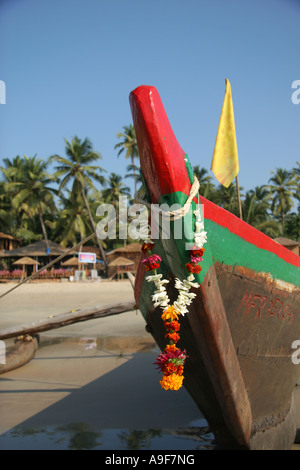 Local fishing boat with a marigold garland hanging from it's bow on the beach in Palolem, Southern Goa, India Stock Photo