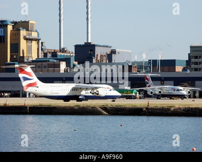 London City Airport British Airways 4 engine passenger jet aircraft taxing on runway beside old dock waters East London Docklands Newham England UK Stock Photo