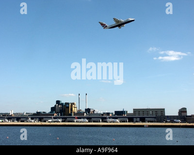Plane taking off from London City Airport over the airport buildings & Tate an Lyle Sugar factory and aircraft on parking stands below Silvertown UK Stock Photo