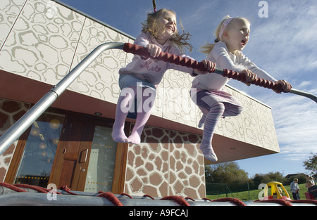 Two four 4 year old girls bounce with glee on a trampoline Stock Photo