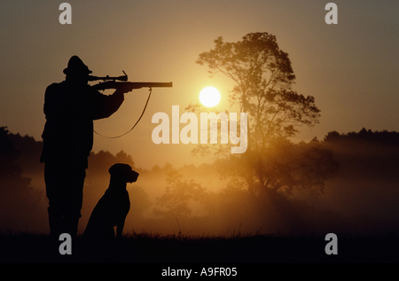 hunter with hunting dog, taking aim with riffle. Stock Photo