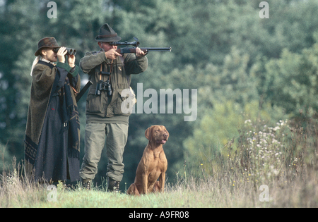 two hunters with hunting dog, taking aim with riffle. Stock Photo
