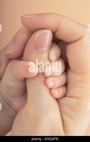 Baby grabbing mothers thumb Stock Photo