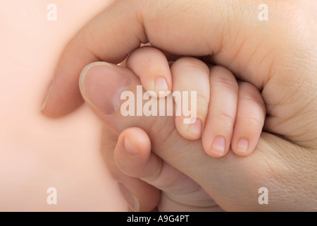 Baby hand sticking to mothers hand Stock Photo