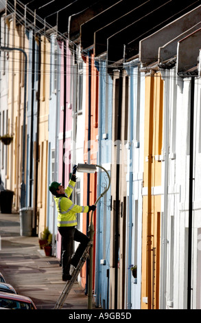 Brighton and Hove City Council worker Alan Stone checks a street lamp on a road of  brightly painted terrace houses in Brighton Stock Photo