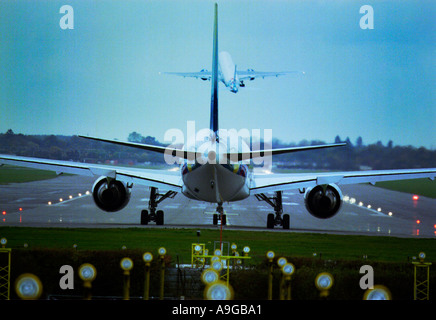 Jet aircraft prepares for takeoff on the runway at Gatwick as a British Airways Boeing 767 takes off for America just ahead Stock Photo