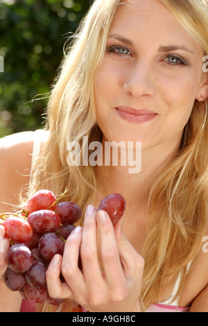 blond woman eating grapes. Stock Photo