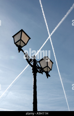 Aircraft jet trails cross high above traditional lamp post in Villefranche, Cote d'Azure, France Stock Photo
