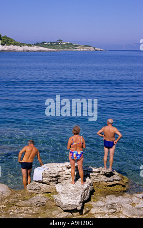 people in bathing suit standing in front of the transparent waters of Paxos Island Greece Stock Photo