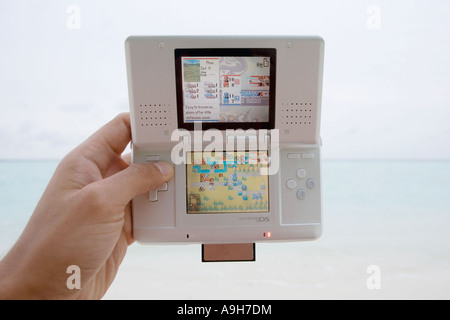 Playing a Nintendo DS on a tropical beach Stock Photo