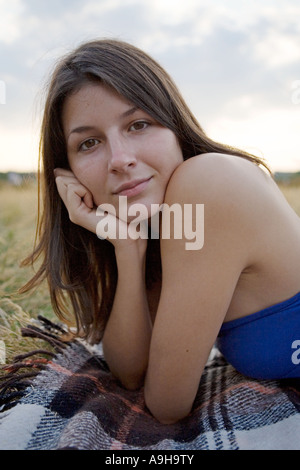 Portrait of a beautiful girl lying down on a blanket outdoors at dusk Stock Photo