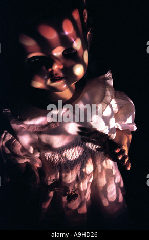 scary doll in the dark with patterned light shining on its face Stock Photo