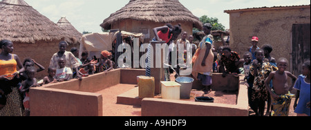 African women pumping potable water in the village centre near Siguri Guinea West Africa Stock Photo