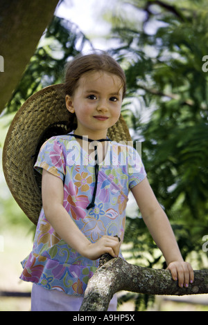 SOUTH CAROLINA YORK Beautiful young girl with pigtails gazes at the camera as she climbs a mimosa tree on a rural farm Stock Photo