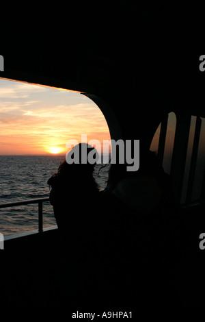 Couple on deck of cross channel ferry silhouetted against sunset Stock Photo