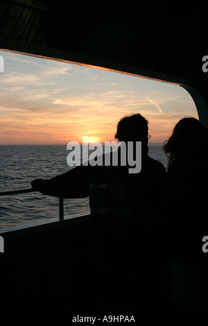 Couple on deck of cross channel ferry silhouetted against sunset Stock Photo