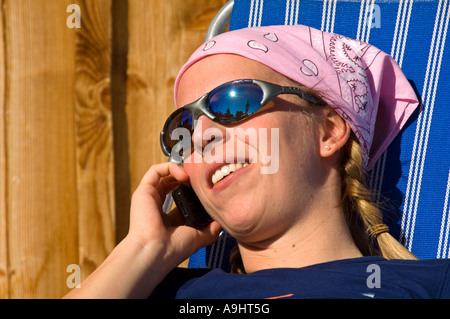Young woman in deck chair talking on her mobile phone Stock Photo