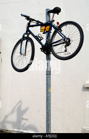 A Raleigh Mountain bike is secured on top of a parking restriction pole on a city road. Stock Photo
