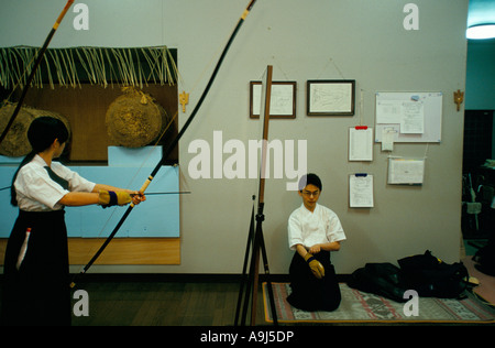 Two Kyudo students at a dojo in Kyoto Japan The girl is facing a makiwara a straw target into which she will drive an arrow Stock Photo