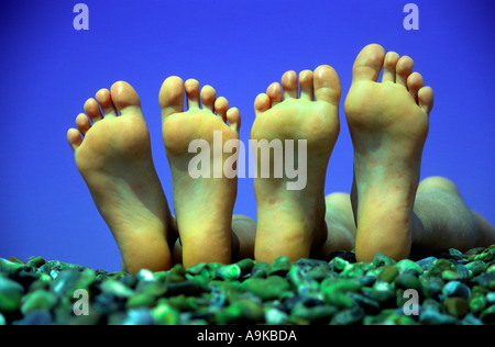 Two pairs of feet on shingle beach Stock Photo