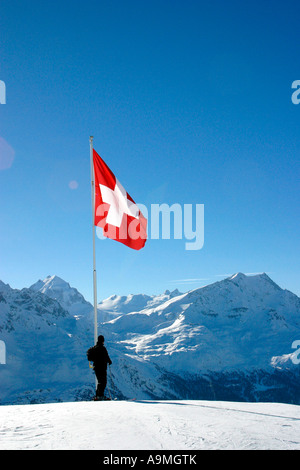 Skier below a Swiss flag looking towards the Corvatsch mountain range with Piz Bernina on the left Stock Photo