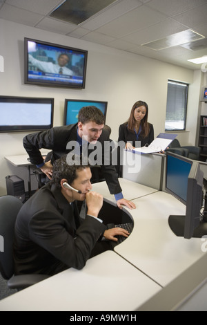 Co-workers in an office looking at a computer screen Stock Photo