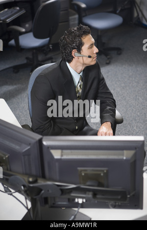Office worker in a suit with headset sitting at his desk Stock Photo
