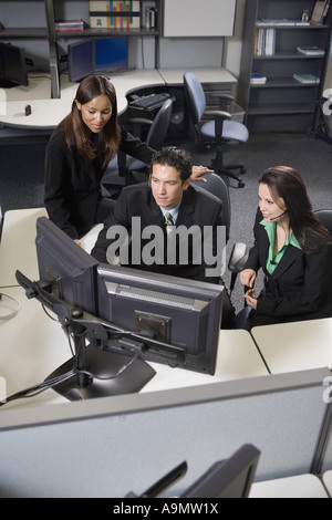 Co-workers working together at a desk looking at computer screens Stock Photo
