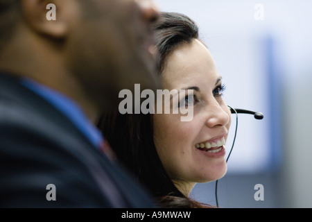 Business woman using headset with colleague in foreground Stock Photo