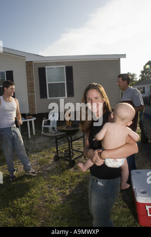 Woman holding baby in backyard, grill in background Stock Photo