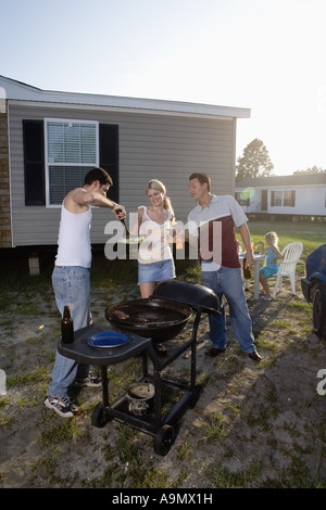 Blue collar families enjoying a cookout in front of trailer home Stock Photo