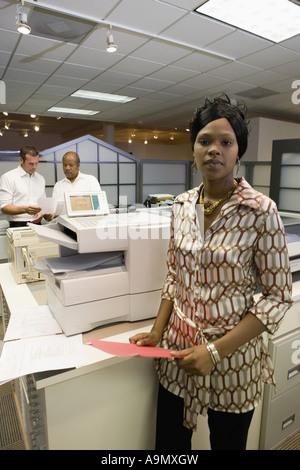 Portrait of a young woman next to copier in the office Stock Photo