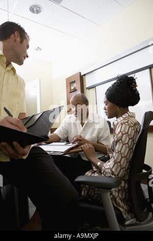 Mature businessman working closely with younger man and woman in a conference room Stock Photo